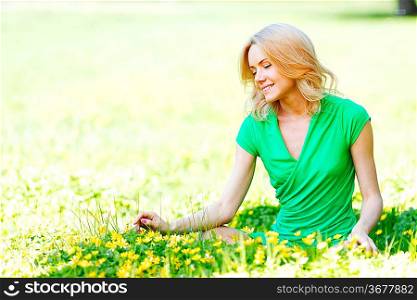 Beautiful young woman sitting on flower field