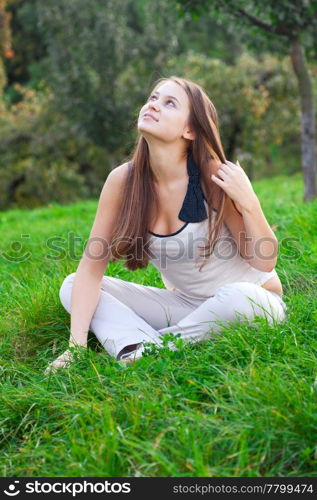 beautiful young woman sitting on green grass