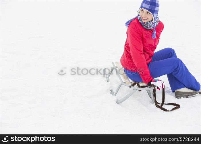 Beautiful young woman sitting on sled