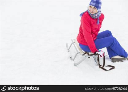 Beautiful young woman sitting on sled