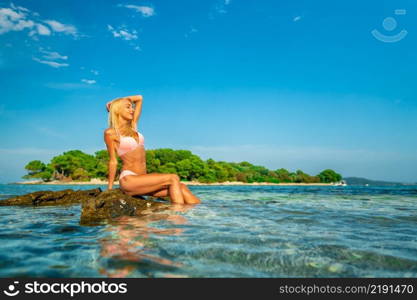 Beautiful young woman sitting on the rocks at Blue lagoon beach in Croatia, Europe. Beautiful young woman sitting on the rocks at Blue lagoon beach in Croatia