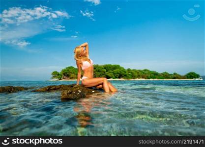 Beautiful young woman sitting on the rocks at Blue lagoon beach in Croatia, Europe. Beautiful young woman sitting on the rocks at Blue lagoon beach in Croatia