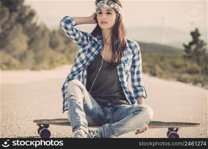 Beautiful young woman sitting over a skateboard