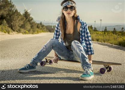 Beautiful young woman sitting over a skateboard