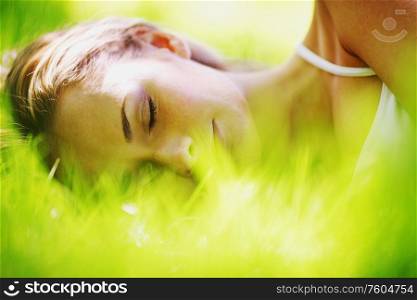 Beautiful young woman sleep on green spring grass. Woman sleep on grass