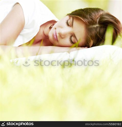 Beautiful young woman sleeping on grass outdoors