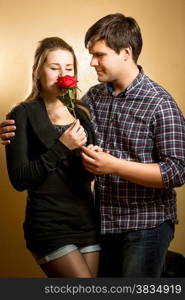 Beautiful young woman smelling red rose presented by young man