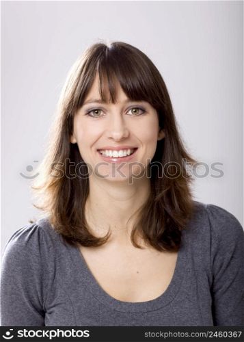 Beautiful young woman smiling, against a gray background