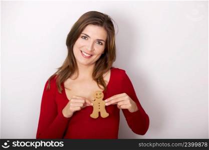 Beautiful young woman smiling and holding a gingerbread cookie