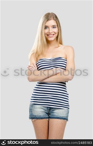Beautiful young woman smiling and standing over a gray background