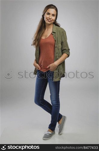 Beautiful young woman smiling and standing over a gray background