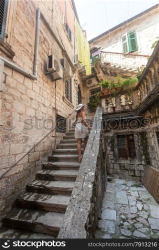 Beautiful young woman standing on old staircase at yard