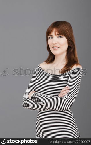 Beautiful young woman standing over a gray background with hands folded