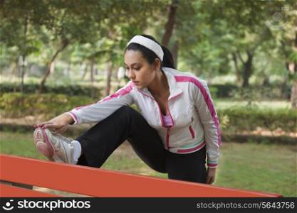 Beautiful young woman stretching in park