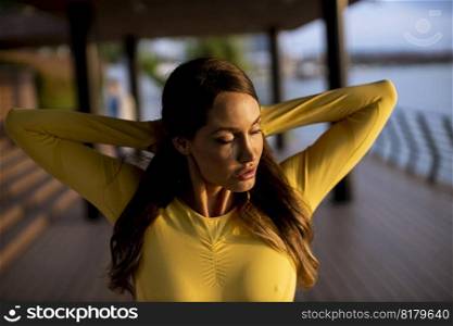 Beautiful young woman stretching on the riverside