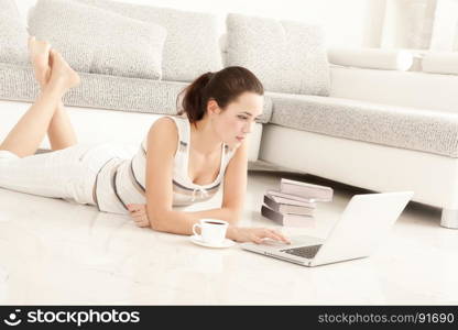 Beautiful Young Woman Student Surfing the Internet Online on Laptop, Drinking Coffee, Lying on the Floor in Living Room