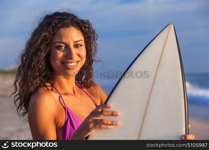 Beautiful young woman surfer girl in bikini with surfboard standing in the surf on a beach
