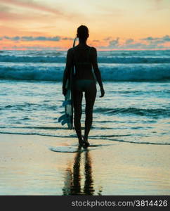 Beautiful young woman surfer with board on the beach