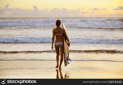 Beautiful young woman surfer with board on the beach