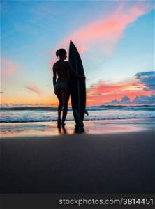 Beautiful young woman surfer with board on the beach