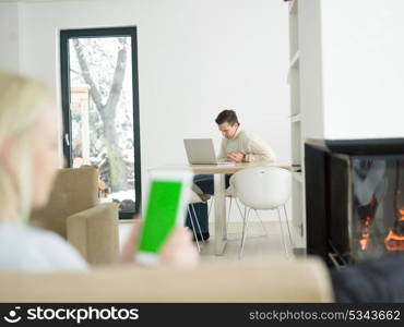 beautiful young woman surfing web using tablet computer in front of fireplace on cold winter day at home