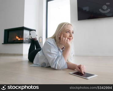 beautiful young woman surfing web using tablet computer on the floor in front of fireplace on cold winter day at home