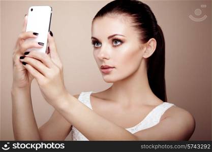 Beautiful young woman taking selfie. Girl photographing herself with phone. Beauty fashion. Eyelashes. Cosmetic Eyeshadow