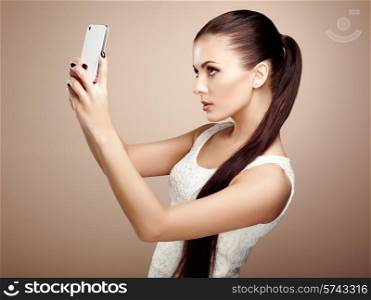Beautiful young woman taking selfie. Girl photographing herself with phone. Beauty fashion. Eyelashes. Cosmetic Eyeshadow