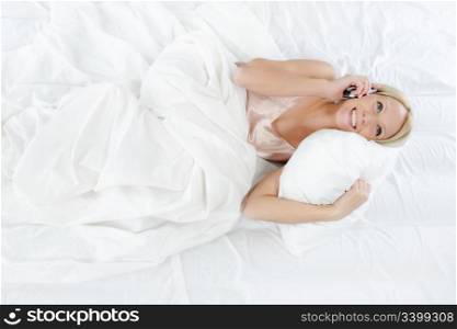 beautiful young woman talking on the phone while lying in bed