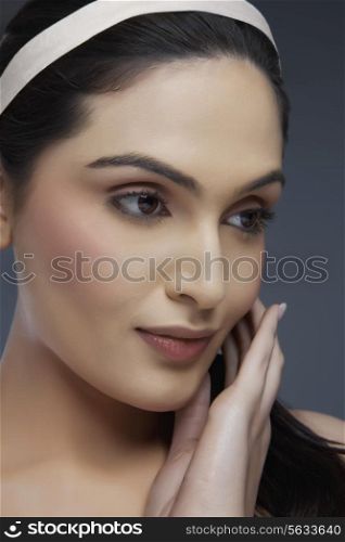 Beautiful young woman touching her face over colored background