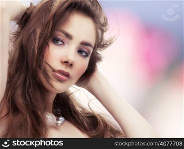 Beautiful young woman touching her hair on colorful background
