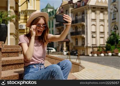 Beautiful Young Woman tourist sitting on stairs using smartphone making video call or selfie.. Beautiful Young Woman tourist sitting on stairs using smartphone making video call or selfie