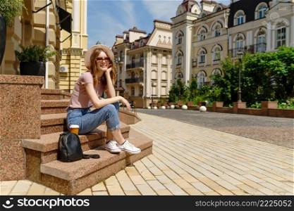 Beautiful Young Woman tourist with takeout coffee sitting on stairs.. Beautiful Young Woman tourist with takeout coffee sitting on stairs