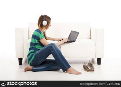 Beautiful young woman using a laptop and listen music, isolated on white