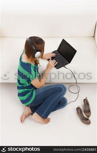 Beautiful young woman using a laptop and listen music, isolated on white