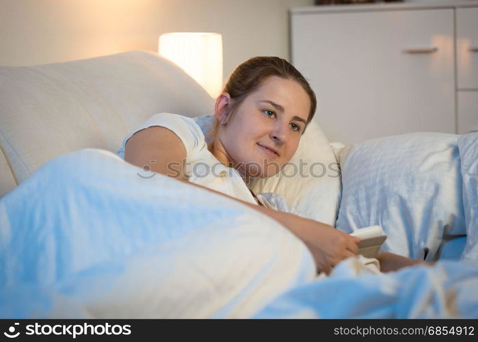 Beautiful young woman using digital tablet in bed at night