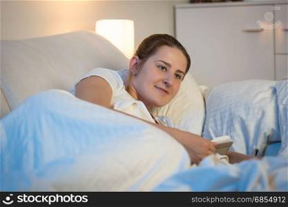 Beautiful young woman using digital tablet in bed at night