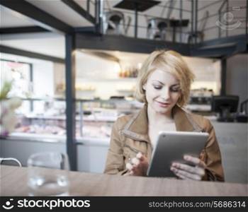 Beautiful young woman using digital tablet in cafe