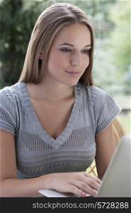 Beautiful young woman using laptop outdoors