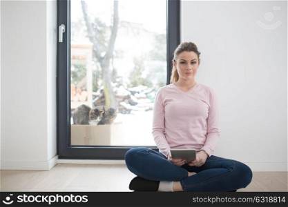 beautiful young woman using tablet computer on the floor at home with cats on snow in background