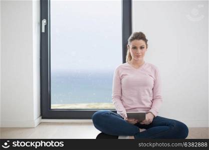 beautiful young woman using tablet computer on the floor at home with cats on snow in background