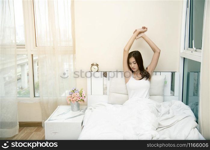 Beautiful young woman waking up after a night sleep. Girl stretching after wake up.