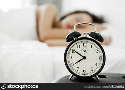 Beautiful young woman waking up with the alarm clock