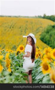 beautiful young woman walking in blooming sunflowers field in summer. Stylish girl with long hair in white dress and hat. summer holiday.. beautiful young woman walking in blooming sunflowers field in summer. Stylish girl with long hair in white dress and hat. summer holiday