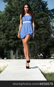 Beautiful young woman walking in summer park