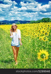 Beautiful young woman walking on fresh sunflowers field, majestic beauty of countryside nature, summer traveling concept