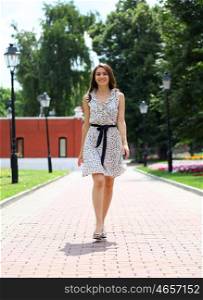 Beautiful young woman walking on the summer park