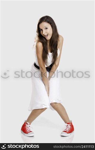 Beautiful young woman wearing a white dress with a pair of red sneakers