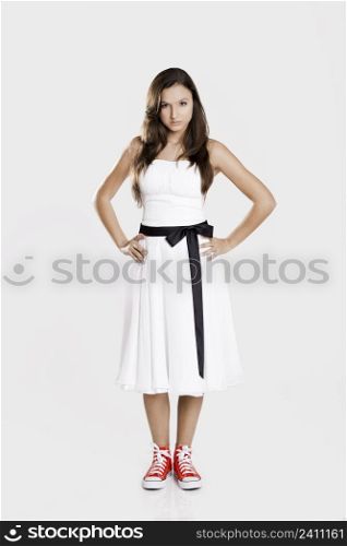 Beautiful young woman wearing a white dress with a pair of red sneakers