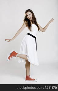 Beautiful young woman wearing a white dress with a pair of red sneakers